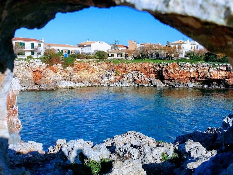 Blick durch einen Felsbogen auf die Küste bei Porto Cristo